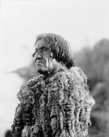 Mohave man, half-length portrait, facing left wearing "primitive" robe of rabbit skin, 1907. Creator: Edward Sheriff Curtis