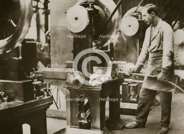 Money making; cutting strips of silver into disks, 20th century. Creator: Unknown.