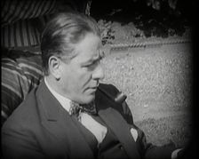 Matheson Lang Relaxing in a Deck Chair Smoking a Pipe, 1920s. Creator: British Pathe Ltd