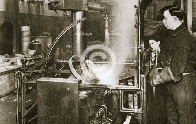 Making money; lowering a pot of liquid metal into a machine, 20th century. Artist: Unknown