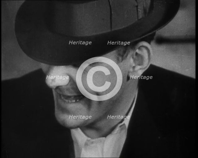 Male American Civilian Wearing a Hat Sitting at a Desk, 1930. Creator: British Pathe Ltd.