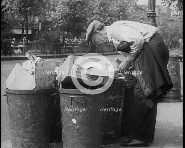 Male American Civilian Hunting Through a Rubbish Bin, 1930. Creator: British Pathe Ltd.