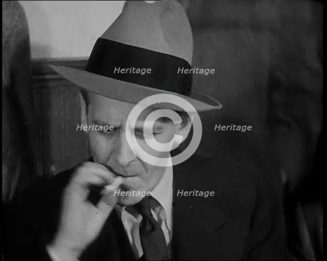 Male American Civilian Smoking a Cigarette While Reporting from the Courtroom During the..., 1930s. Creator: British Pathe Ltd.
