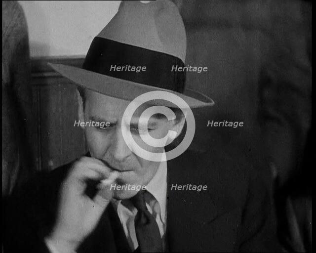 Male American Civilian Smoking a Cigarette While Reporting from the Courtroom During the..., 1930s. Creator: British Pathe Ltd.