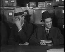 Male American Civilians Wearing Hats Sitting at a Desk, 1930. Creator: British Pathe Ltd