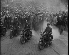 Male American Police Officers Riding Motorbikes Escorting a Large Crowd in a Parade, 1930. Creator: British Pathe Ltd