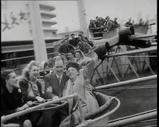 Male and Female Fairgroundgoers Riding in Gondolas Running Along Tracks on a Fairground..., 1938. Creator: British Pathe Ltd