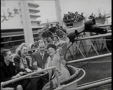 Male and Female Fairgroundgoers Riding in Gondolas Running Along Tracks on a Fairground..., 1938. Creator: British Pathe Ltd