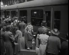 Male and Female Passengers, Some Holding Suitcases, on a Platform of a Large Train Station..., 1938. Creator: British Pathe Ltd