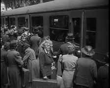 Male and Female Passengers, Some Holding Suitcases, on a Platform of a Large Train Station..., 1938. Creator: British Pathe Ltd