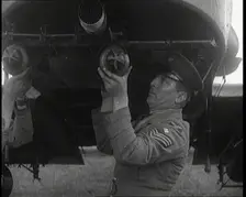 Male British Officers Mounting Bombs Into a Fighter Plane, 1920s. Creator: British Pathe Ltd