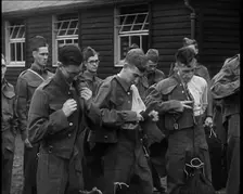Male British Soldiers Putting on The Tunics of Their Uniforms in Front of Wooden Hut, 1939. Creator: British Pathe Ltd