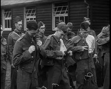 Male British Soldiers Putting on The Tunics of Their Uniforms in Front of Wooden Hut, 1939. Creator: British Pathe Ltd