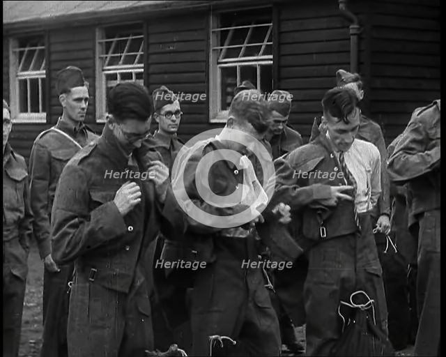 Male British Soldiers Putting on The Tunics of Their Uniforms in Front of Wooden Hut, 1939. Creator: British Pathe Ltd.
