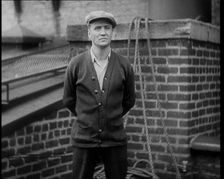 Male Civilian Wearing a Cardigan and a Flatcap Standing in Front of a Wall Talking at the..., 1930. Creator: British Pathe Ltd