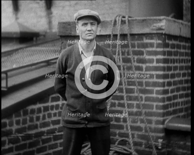 Male Civilian Wearing a Cardigan and a Flatcap Standing in Front of a Wall Talking at the..., 1930. Creator: British Pathe Ltd.
