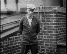 Male Civilian Wearing a Cardigan and a Flatcap Standing in Front of a Wall Talking at the..., 1930. Creator: British Pathe Ltd