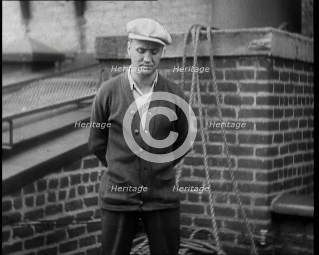 Male Civilian Wearing a Cardigan and a Flatcap Standing in Front of a Wall Talking at the..., 1930. Creator: British Pathe Ltd.