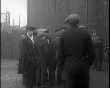 Male Civilian in a Flat Cap Facing a Wall. Another Male Civilian Carries a Sack Over His..., 1924. Creator: British Pathe Ltd