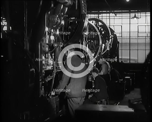 Male Civilians Working Large Presses in a Factory, 1931. Creator: British Pathe Ltd.