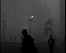 Male Civilians Walking Through the Foggy Streets of London, 1929. Creator: British Pathe Ltd