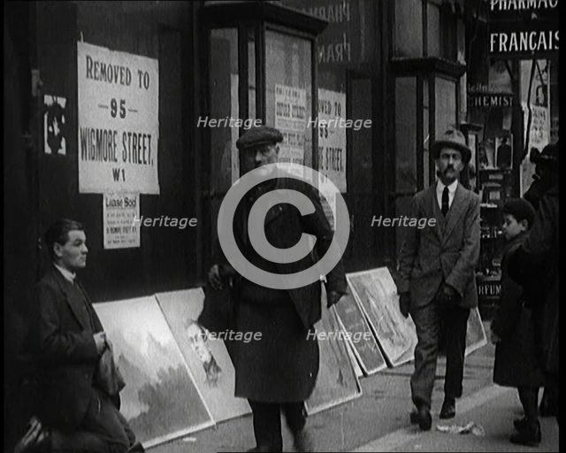 Male Ex-Services Civilian Selling Paintings on a Pavement Whilst Other Civilians are Walk..., 1920s. Creator: British Pathe Ltd.