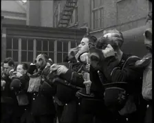 Male Police Civil Defence Volunteers Practice Putting on Gas Masks in a Yard Behind a Brick..., 1938 Creator: British Pathe Ltd