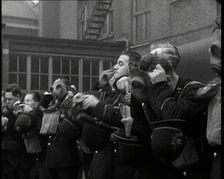 Male Police Civil Defence Volunteers Practice Putting on Gas Masks in a Yard Behind a Brick..., 1938 Creator: British Pathe Ltd
