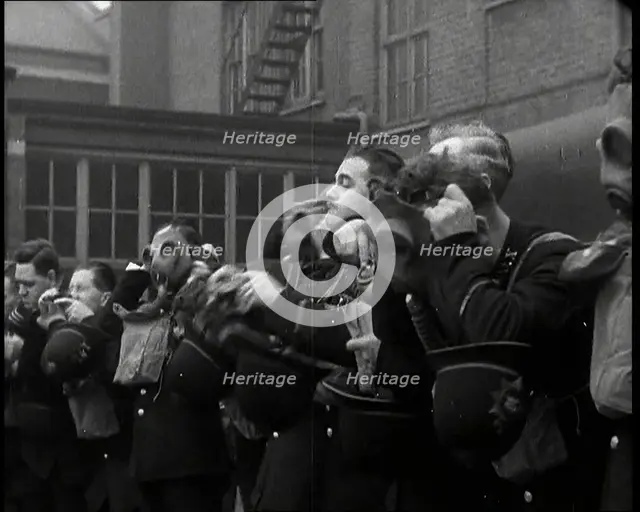 Male Police Civil Defence Volunteers Practice Putting on Gas Masks in a Yard Behind a Brick..., 1938 Creator: British Pathe Ltd.