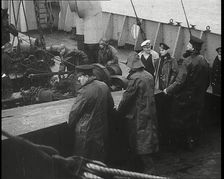 Male Ship's Crew Standing Near Rigging and Machinery on Deck of a Freighter, 1939. Creator: British Pathe Ltd