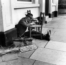 Man mending a chair on an East End street, London, 1950s. Creator: Henry Grant