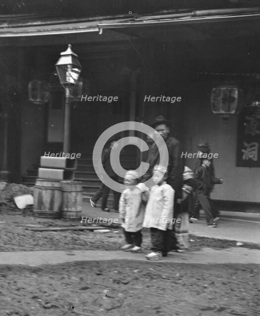 Man and two children crossing a street, Chinatown, San Francisco, between 1896 and 1906. Creator: Arnold Genthe.