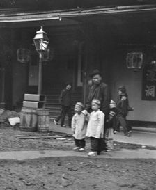 Man and two children crossing a street, Chinatown, San Francisco, between 1896 and 1906. Creator: Arnold Genthe