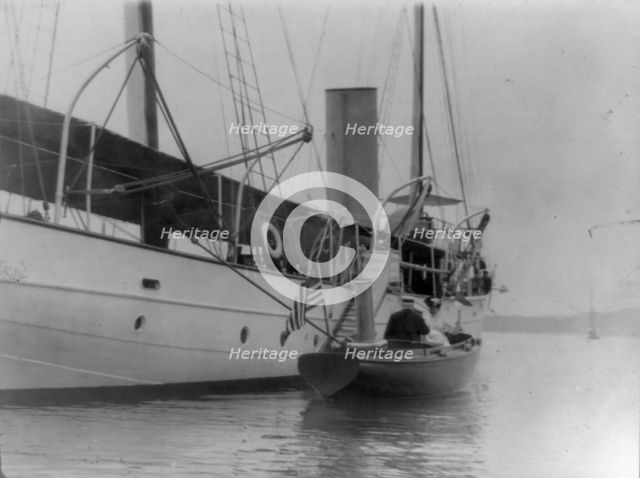 Man and woman in small boat alongside large boat or ship, Oyster Bay, Long Island, N.Y., 1905. Creator: Frances Benjamin Johnston.