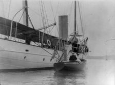 Man and woman in small boat alongside large boat or ship, Oyster Bay, Long Island, N.Y., 1905. Creator: Frances Benjamin Johnston