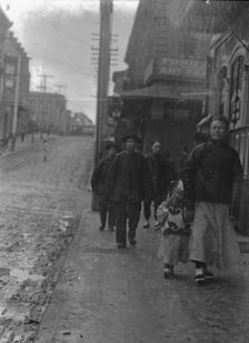 Man and a boy walking down a sidewalk with other people, Chinatown, San Francisco, c1896-1906. Creator: Arnold Genthe