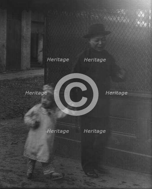 Man and a young child walking down a street, Chinatown, San Francisco, between 1896 and 1906. Creator: Arnold Genthe.