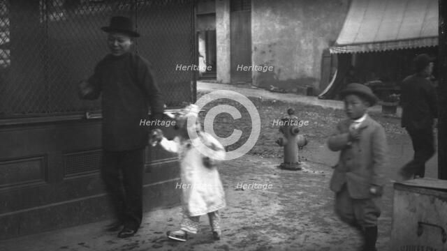 Man and a young child walking down a street, Chinatown, San Francisco, between 1896 and 1906. Creator: Arnold Genthe.