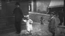 Man and a young child walking down a street, Chinatown, San Francisco, between 1896 and 1906. Creator: Arnold Genthe