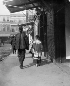 Man and a young girl walking down a sidewalk, Chinatown, San Francisco, between 1896 and 1906. Creator: Arnold Genthe