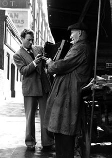 Man browsing a stall at Camden Town, 1950s. Creator: Henry Grant
