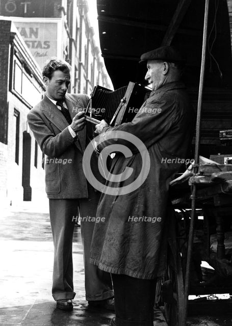Man browsing a stall at Camden Town, 1950s. Creator: Henry Grant.