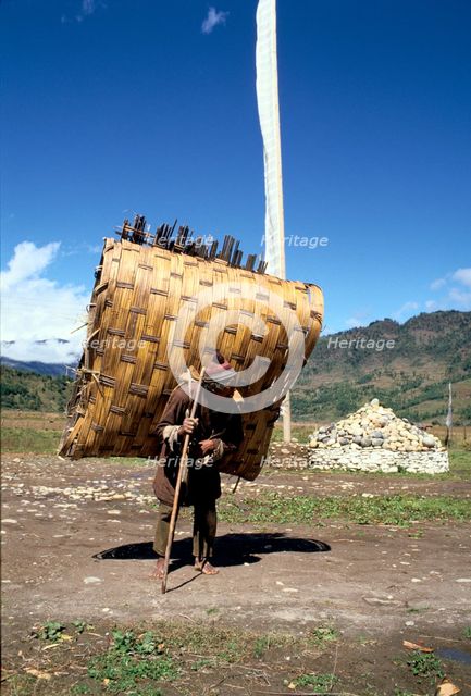 Man carrying a huge load, Bumthang, Bhutan. Creator: Vivienne Sharp.