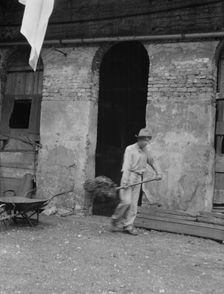 Man cleaning out a small building, New Orleans or Charleston, South Carolina, between 1920 and 1926. Creator: Arnold Genthe