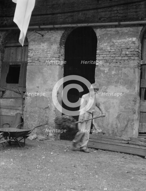 Man cleaning out a small building, New Orleans or Charleston, South Carolina, between 1920 and 1926. Creator: Arnold Genthe.