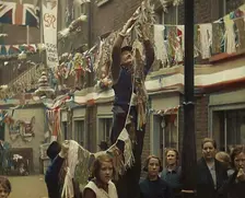 Man Hanging Bunting from a Lamp Post in a Street With Decorations For the Coronation of..., 1937. Creator: British Pathe Ltd