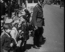 Man in Uniform Helping Young Children Cross the Road, 1933. Creator: British Pathe Ltd