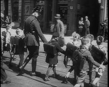 Man in Uniform Helping Young Children Cross the Road, 1933. Creator: British Pathe Ltd