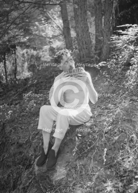 Man playing panpipes in the woods, between 1911 and 1942. Creator: Arnold Genthe.