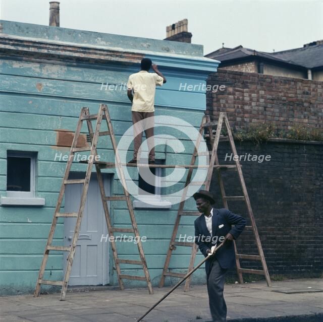 Man re-painting the exterior of a business premises in Kentish Town, London. 1960s. Artist: John Gay.